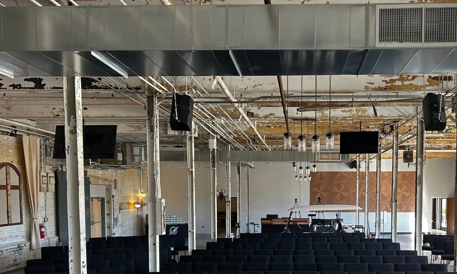 The Loom at Gibson Mill, a long brick hall with timber beams and a stage at the far end